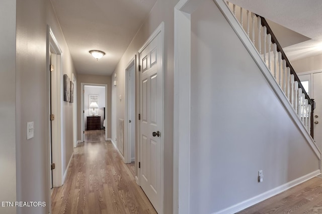 hallway featuring light hardwood / wood-style floors and a textured ceiling