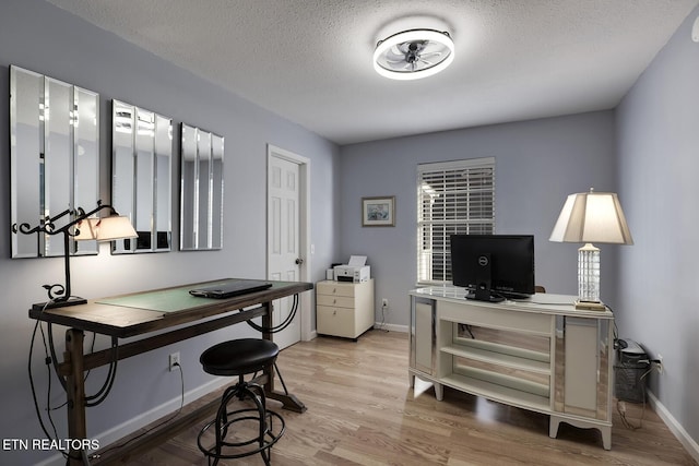 office featuring light wood-type flooring and a textured ceiling