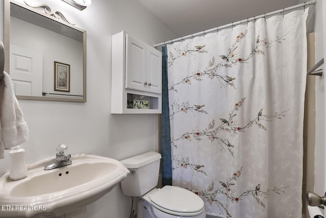 bathroom featuring sink, toilet, and a shower with shower curtain