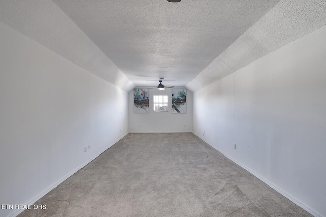 carpeted spare room with ceiling fan, a textured ceiling, and lofted ceiling