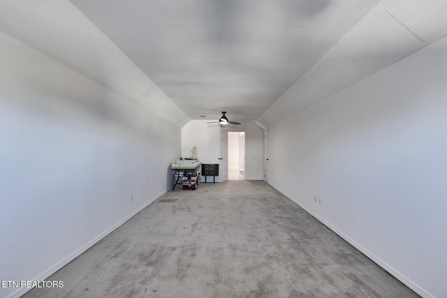 interior space featuring ceiling fan, light colored carpet, a textured ceiling, and vaulted ceiling