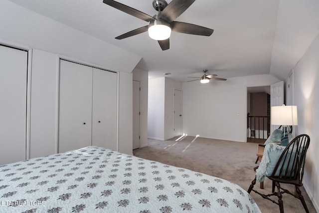 bedroom with multiple closets, ceiling fan, vaulted ceiling, and light carpet