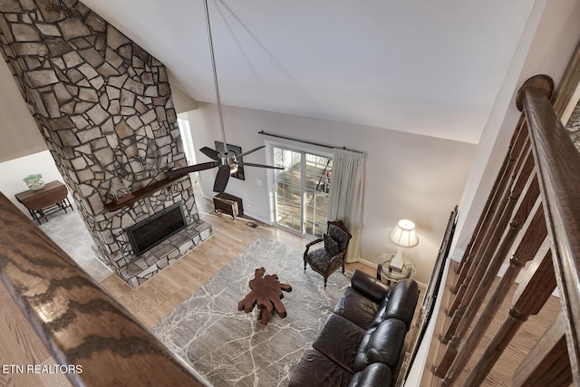 unfurnished living room featuring light wood-type flooring, ceiling fan, a stone fireplace, and lofted ceiling