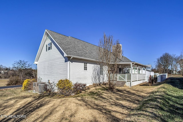 rear view of property featuring central AC unit, a porch, and a lawn