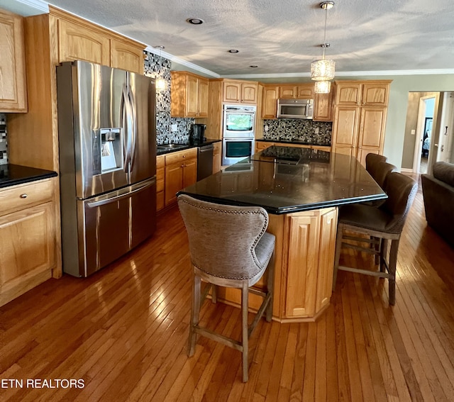 kitchen featuring a kitchen island, pendant lighting, decorative backsplash, stainless steel appliances, and crown molding