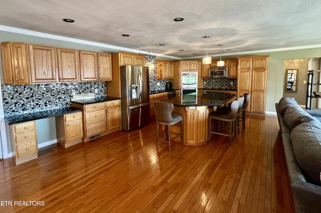 kitchen featuring pendant lighting, crown molding, appliances with stainless steel finishes, built in desk, and a kitchen island