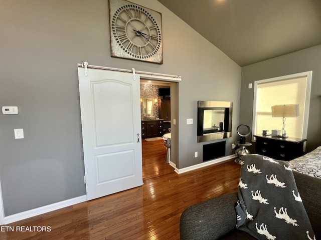 bedroom with lofted ceiling, a barn door, and hardwood / wood-style floors