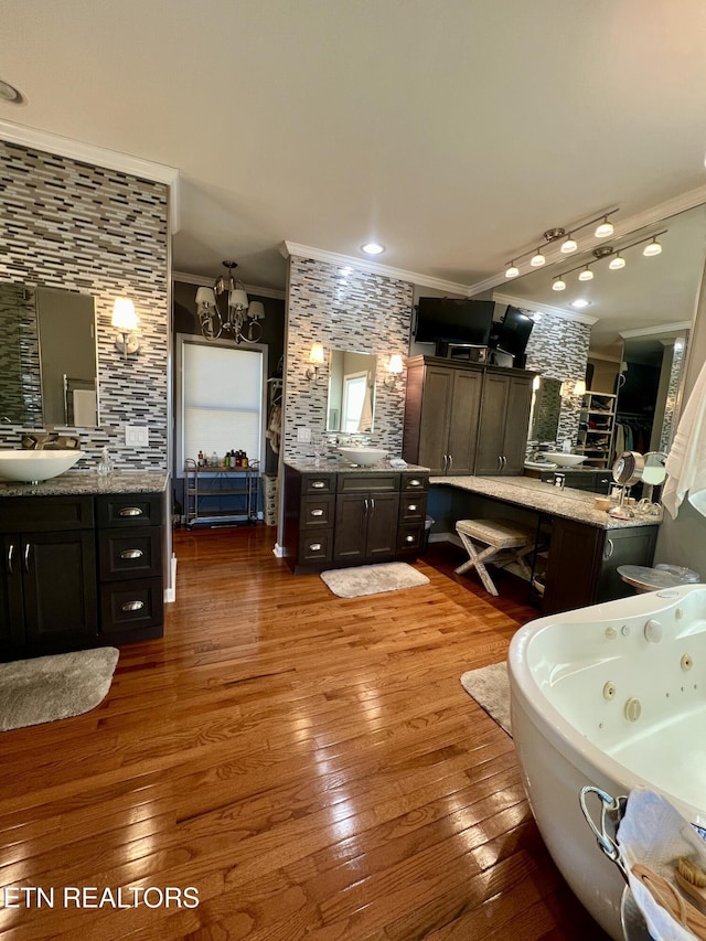 bathroom with a tub to relax in, ornamental molding, vanity, a notable chandelier, and hardwood / wood-style flooring