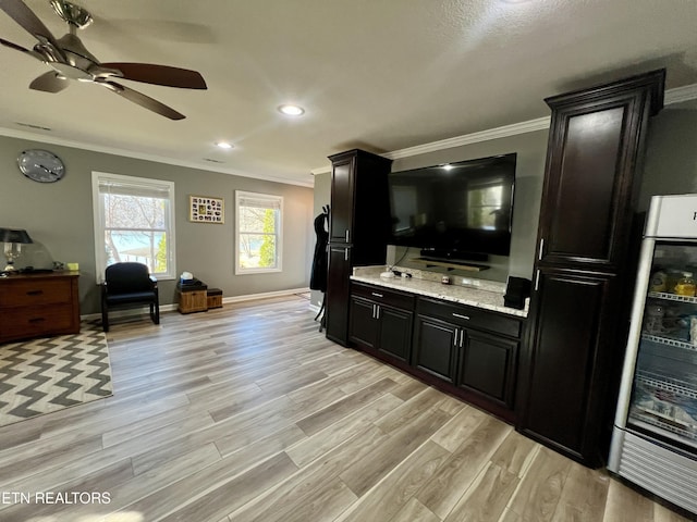 kitchen featuring crown molding, light hardwood / wood-style flooring, light stone countertops, and beverage cooler