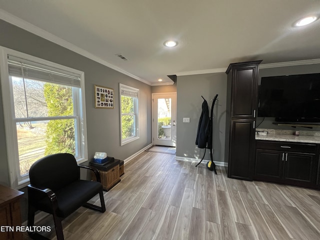 living area with crown molding and light hardwood / wood-style flooring