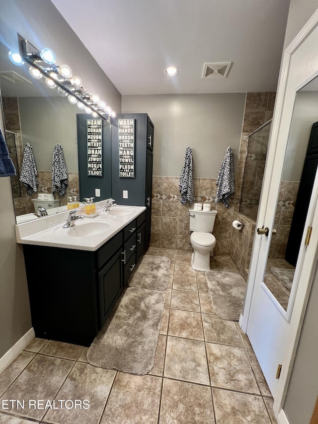 bathroom featuring tile walls, vanity, a tile shower, tile patterned floors, and toilet