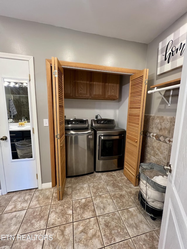 clothes washing area with tile patterned flooring, independent washer and dryer, and cabinets