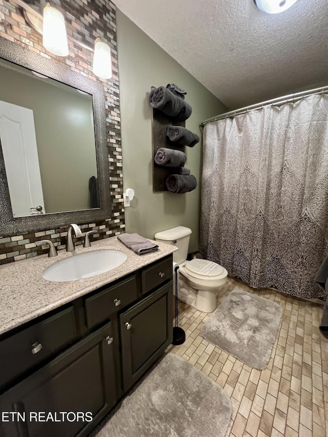 bathroom with tasteful backsplash, vanity, toilet, and a textured ceiling