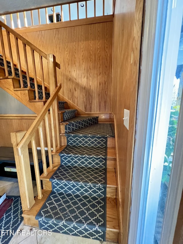 stairway featuring wood walls