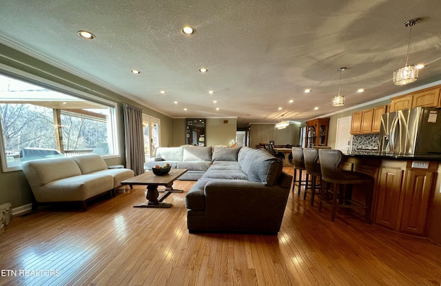 living room featuring ornamental molding, light hardwood / wood-style floors, and a textured ceiling