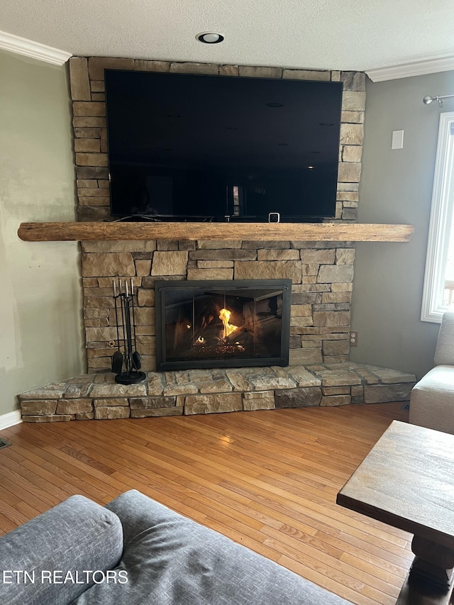 details with a stone fireplace, ornamental molding, a textured ceiling, and hardwood / wood-style flooring