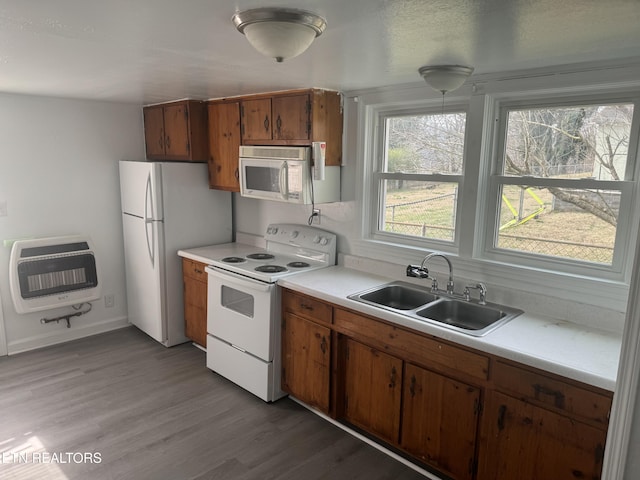 kitchen featuring heating unit, sink, white appliances, and light hardwood / wood-style floors