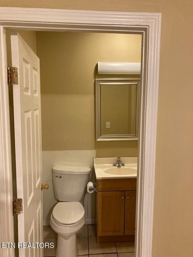 bathroom with toilet, vanity, and tile patterned floors