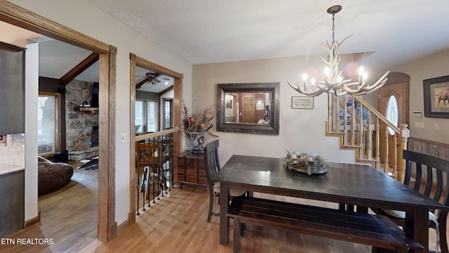 dining space featuring lofted ceiling, wood-type flooring, and ceiling fan with notable chandelier