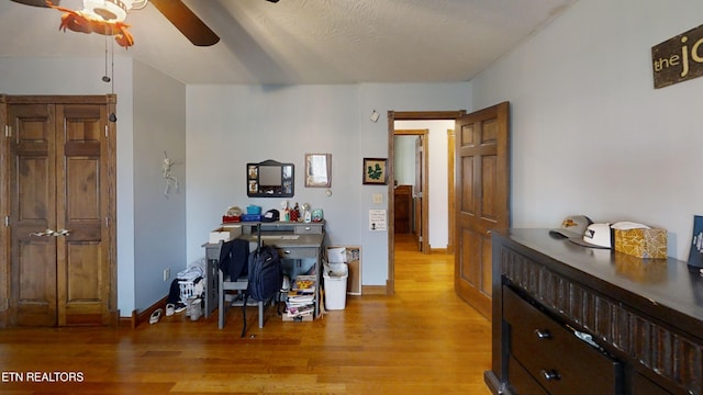 home office with a textured ceiling, ceiling fan, and light hardwood / wood-style flooring