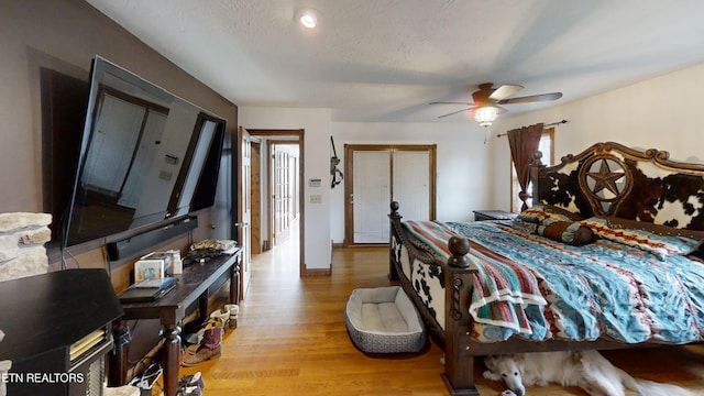 bedroom with a textured ceiling, light hardwood / wood-style floors, and ceiling fan