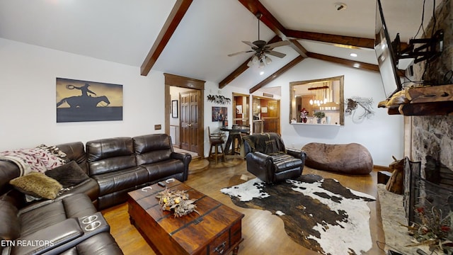 living room featuring ceiling fan, a fireplace, lofted ceiling with beams, and light wood-type flooring