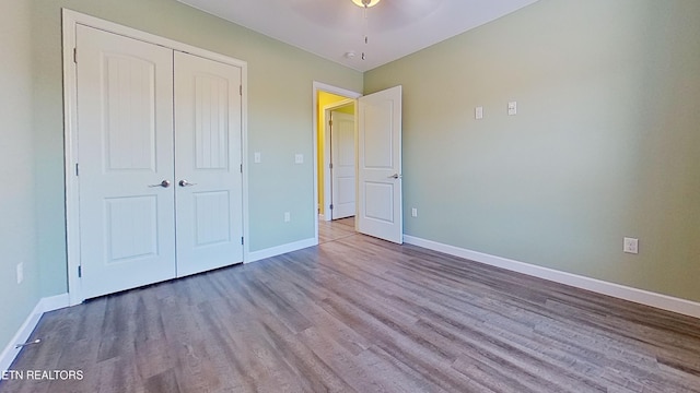 unfurnished bedroom featuring ceiling fan, wood-type flooring, and a closet