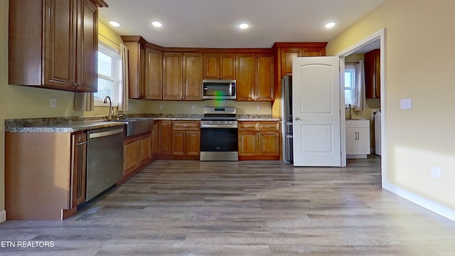 kitchen with appliances with stainless steel finishes, sink, and light hardwood / wood-style floors