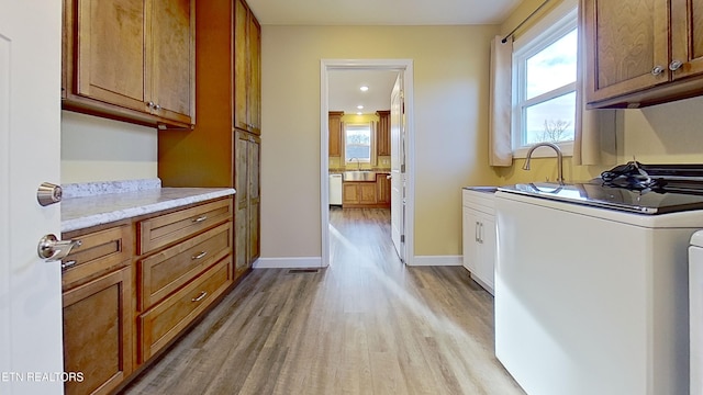 washroom with cabinets, plenty of natural light, sink, and light hardwood / wood-style flooring