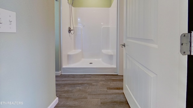 bathroom with hardwood / wood-style flooring and a shower