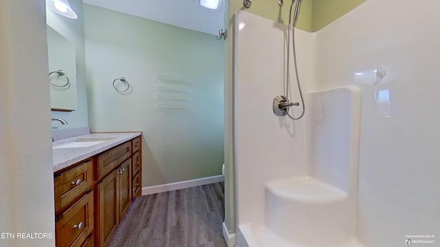 bathroom featuring hardwood / wood-style flooring, vanity, and a shower