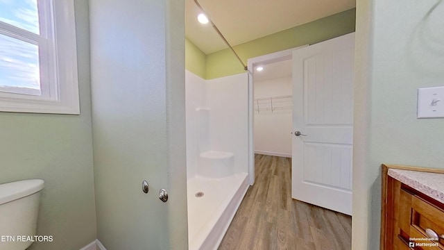 bathroom featuring hardwood / wood-style flooring, a shower, vanity, and toilet