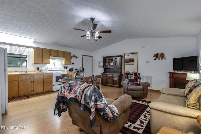 living room featuring lofted ceiling, ceiling fan, sink, light hardwood / wood-style flooring, and a textured ceiling