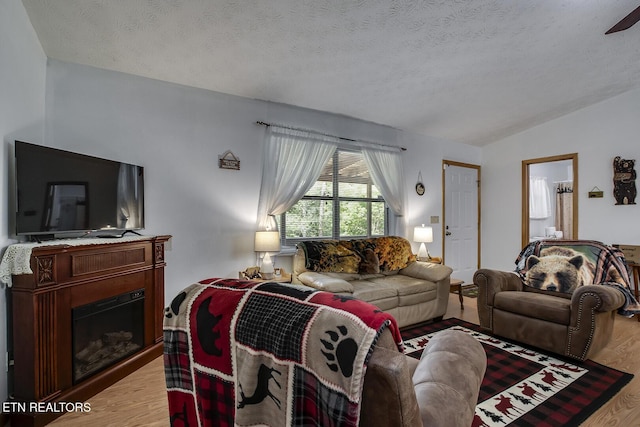 living room featuring lofted ceiling, a textured ceiling, and light hardwood / wood-style flooring