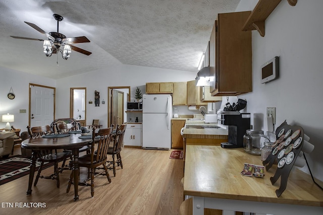 dining space featuring a textured ceiling, ceiling fan, lofted ceiling, and light hardwood / wood-style flooring