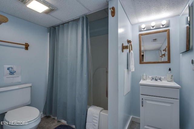 bathroom featuring toilet, tile patterned floors, a drop ceiling, and vanity