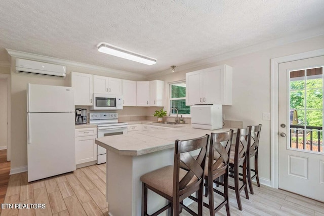 kitchen with white appliances, white cabinets, a kitchen bar, sink, and kitchen peninsula