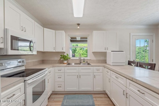 kitchen with sink, white appliances, and white cabinetry