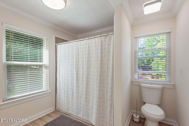 bathroom featuring a textured ceiling, hardwood / wood-style floors, toilet, ornamental molding, and a shower with shower curtain