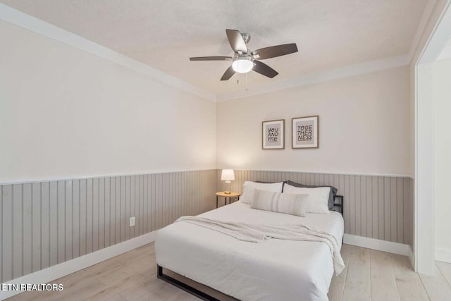 bedroom featuring ceiling fan, light wood-type flooring, crown molding, and a textured ceiling