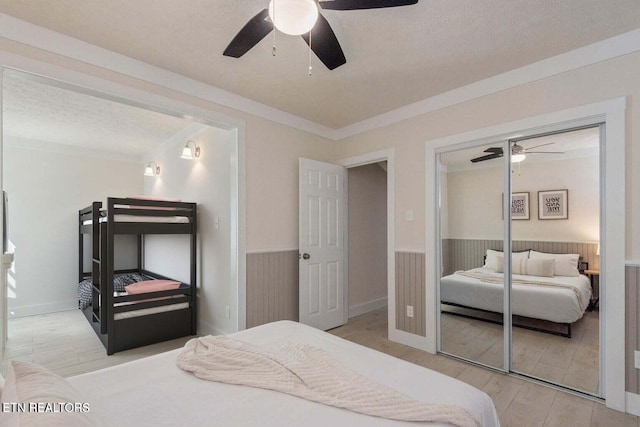 bedroom with a textured ceiling, hardwood / wood-style flooring, a closet, ornamental molding, and ceiling fan