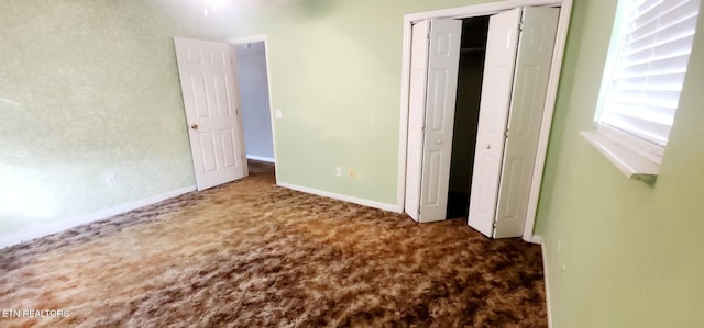 unfurnished bedroom with a closet and dark carpet