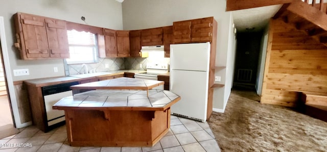 kitchen with light tile patterned floors, tile countertops, white appliances, a kitchen island, and sink