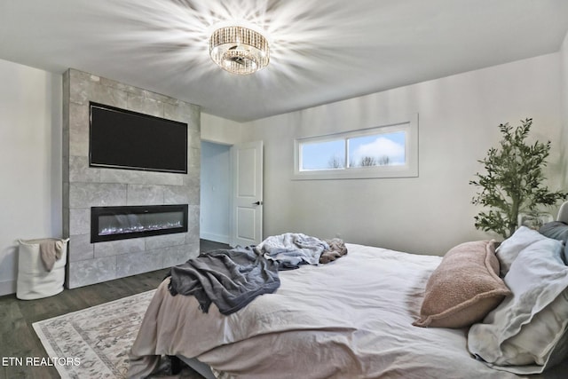 bedroom with dark hardwood / wood-style floors and a tile fireplace