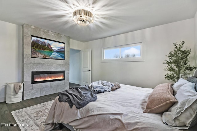 bedroom with dark wood-type flooring and a tiled fireplace