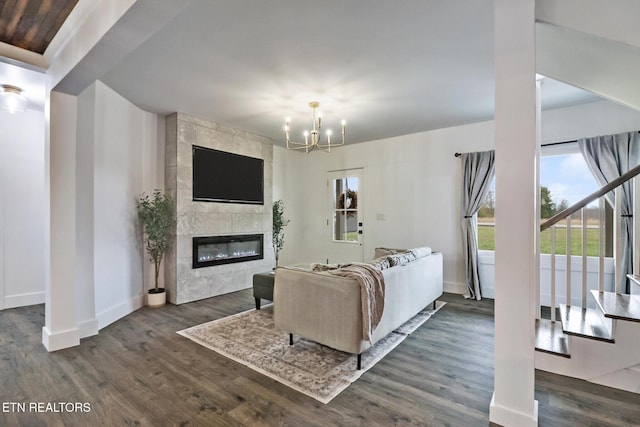 living room featuring dark wood-type flooring, a tile fireplace, and a chandelier