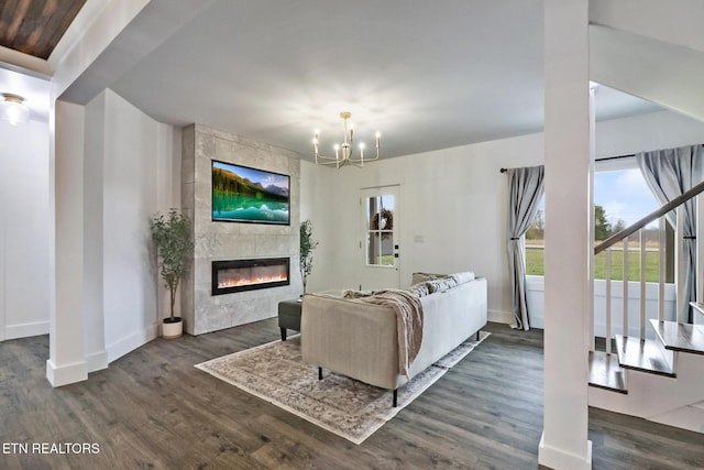 living room featuring dark hardwood / wood-style floors, a tiled fireplace, and an inviting chandelier