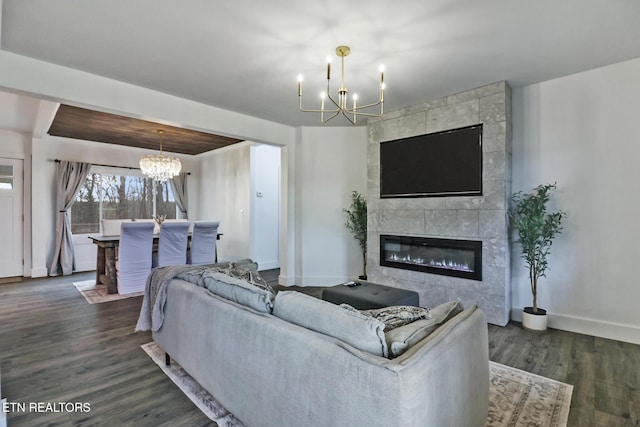 living room featuring dark hardwood / wood-style floors, a tile fireplace, and an inviting chandelier