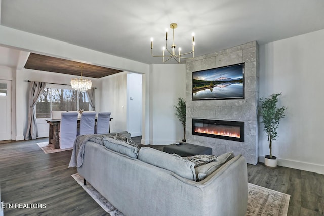 living room featuring dark hardwood / wood-style floors, a tile fireplace, and an inviting chandelier