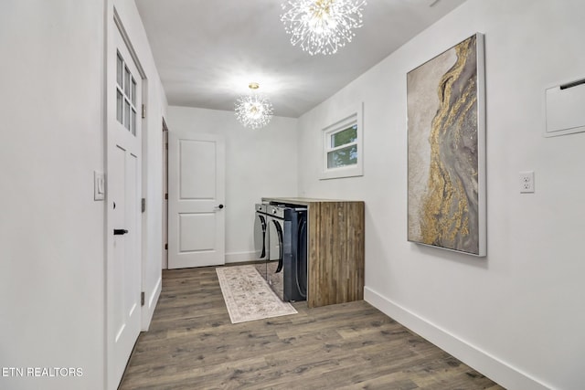 clothes washing area featuring dark wood-type flooring, independent washer and dryer, and an inviting chandelier